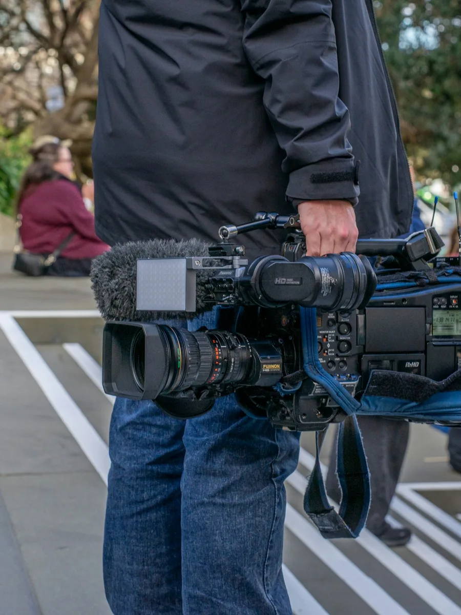 Un cameraman tient une caméra vidéo professionnelle lors d'un rassemblement en extérieur