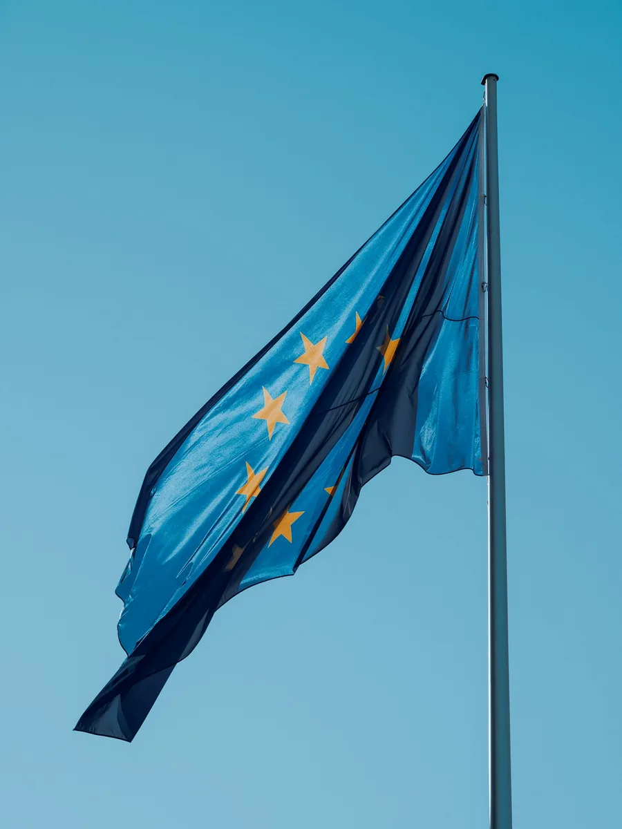 Le drapeau de l'Union européenne flotte au sommet d'un mât sous un ciel bleu