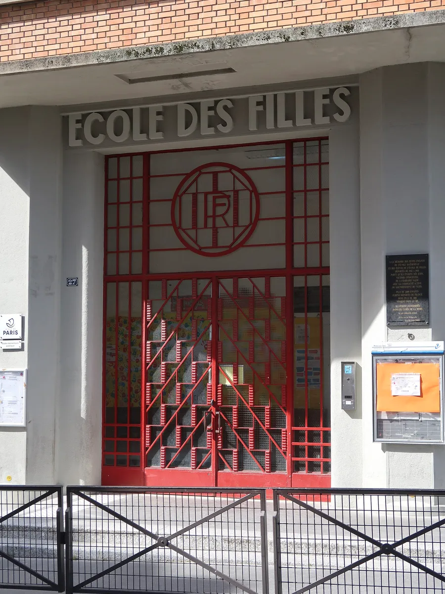 Entrée d'une école du 20e arrondissement de Paris, avec l'inscription ancienne « École des filles » au-dessus d'une grille rouge.