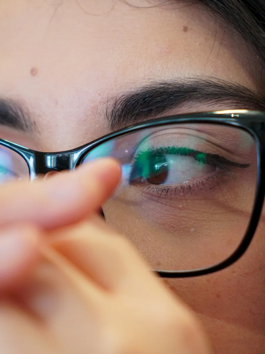 Gros plan sur le regard d'une femme qui ajuste ses lunettes à monture noire