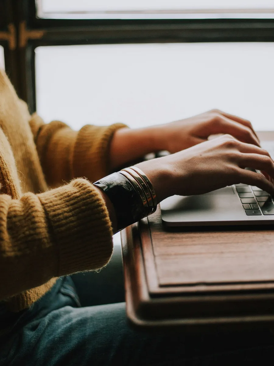 Les mains d'une personne en pull tapent sur le clavier d'un ordinateur portable