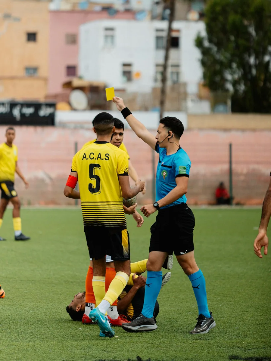 Un arbitre de football brandit un carton jaune pendant un match amateur