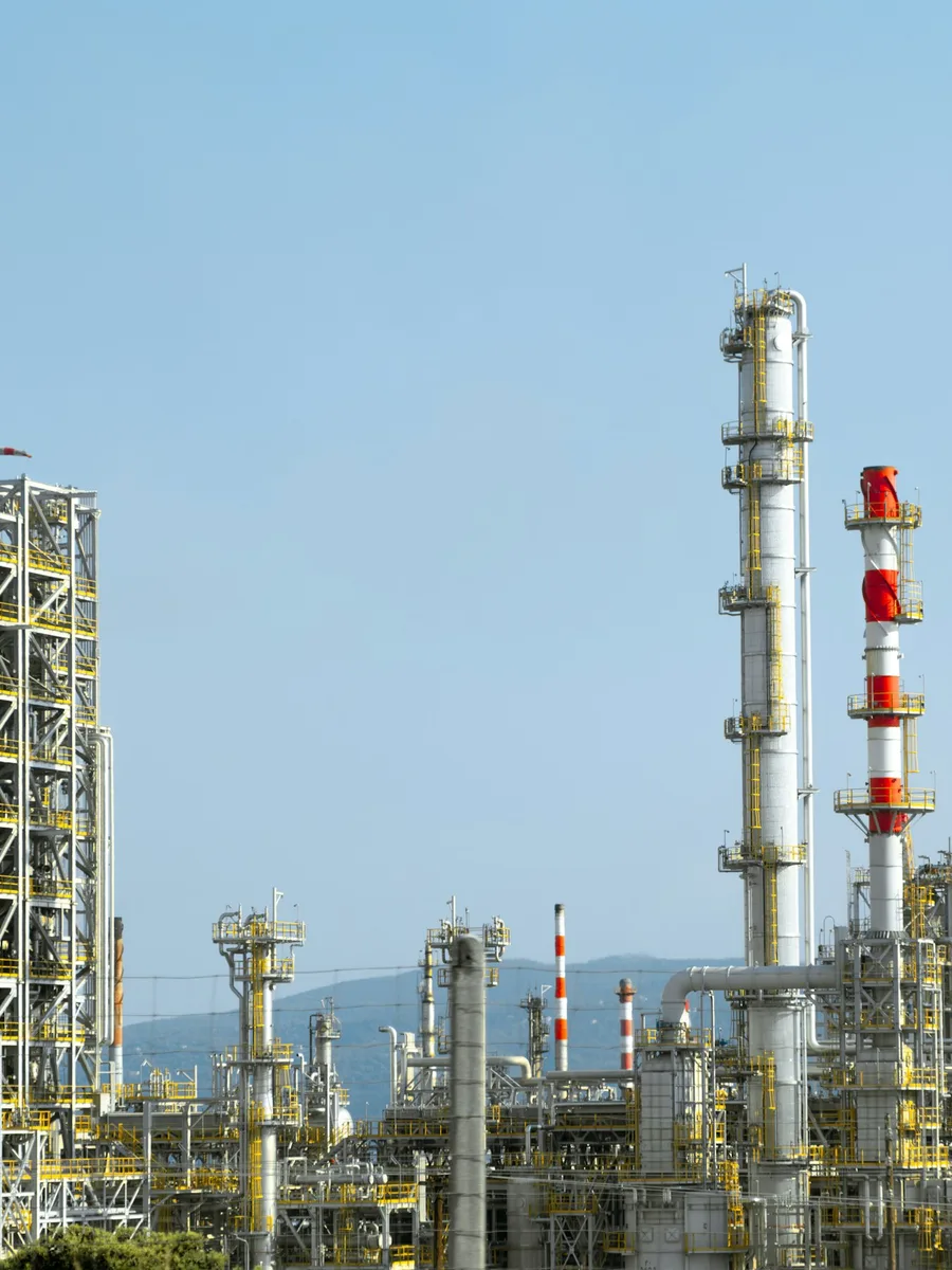 Colonnes et cheminées rouges et blanches d'une raffinerie de pétrole sous un ciel bleu