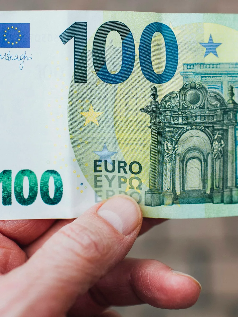 Une main tient un billet de 100 euros.