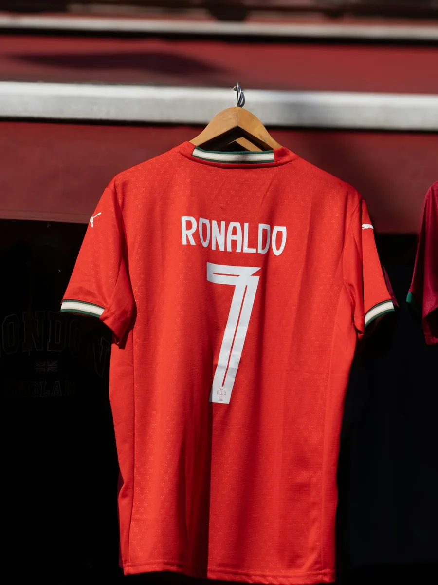 Un maillot de football rouge floqué Ronaldo 7, suspendu sur un cintre dans une boutique