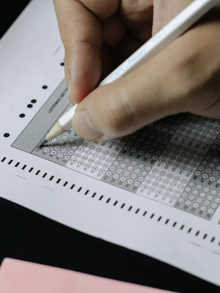 Une main tient un crayon au-dessus d'une feuille de réponses