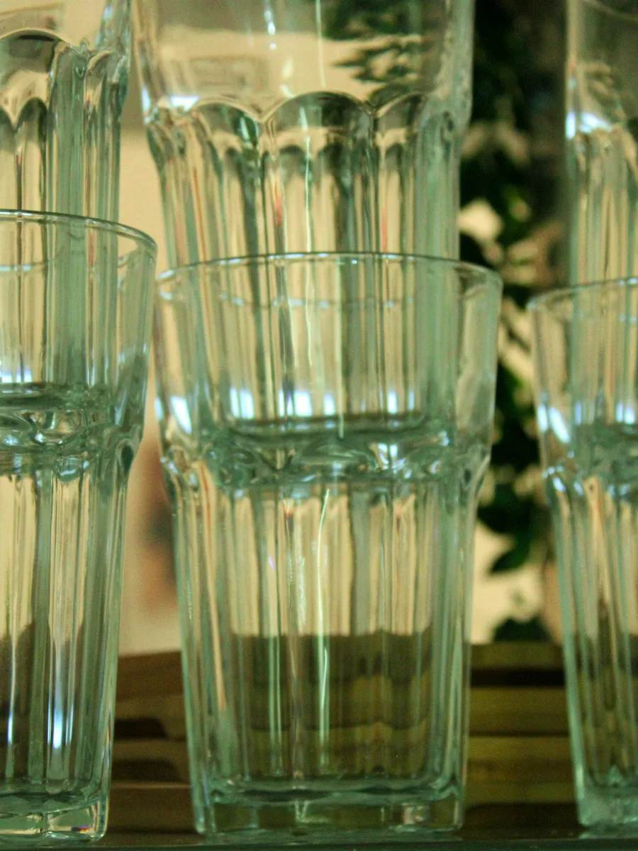 Des verres à eau transparents empilés sur une étagère.