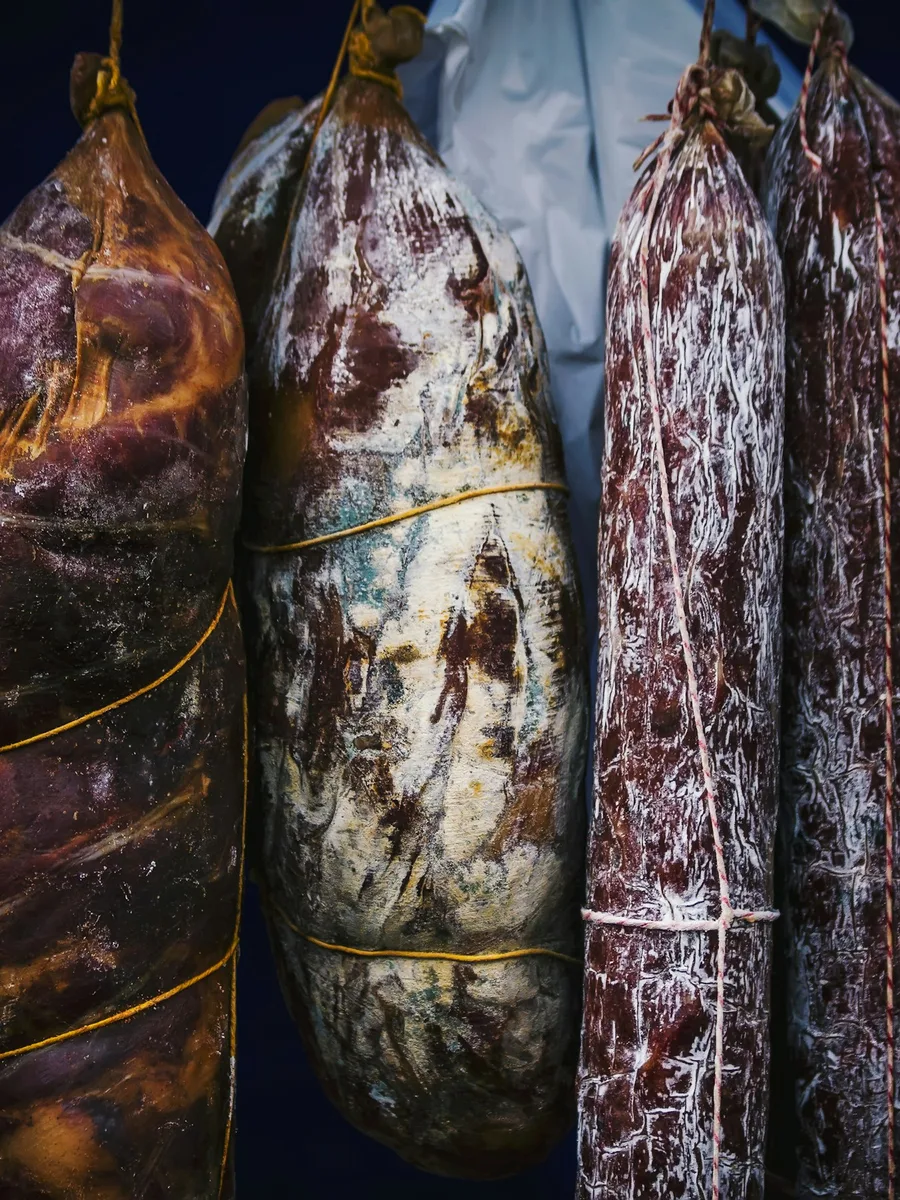 Des saucissons et chorizos séchés suspendus dans une charcuterie, en gros plan