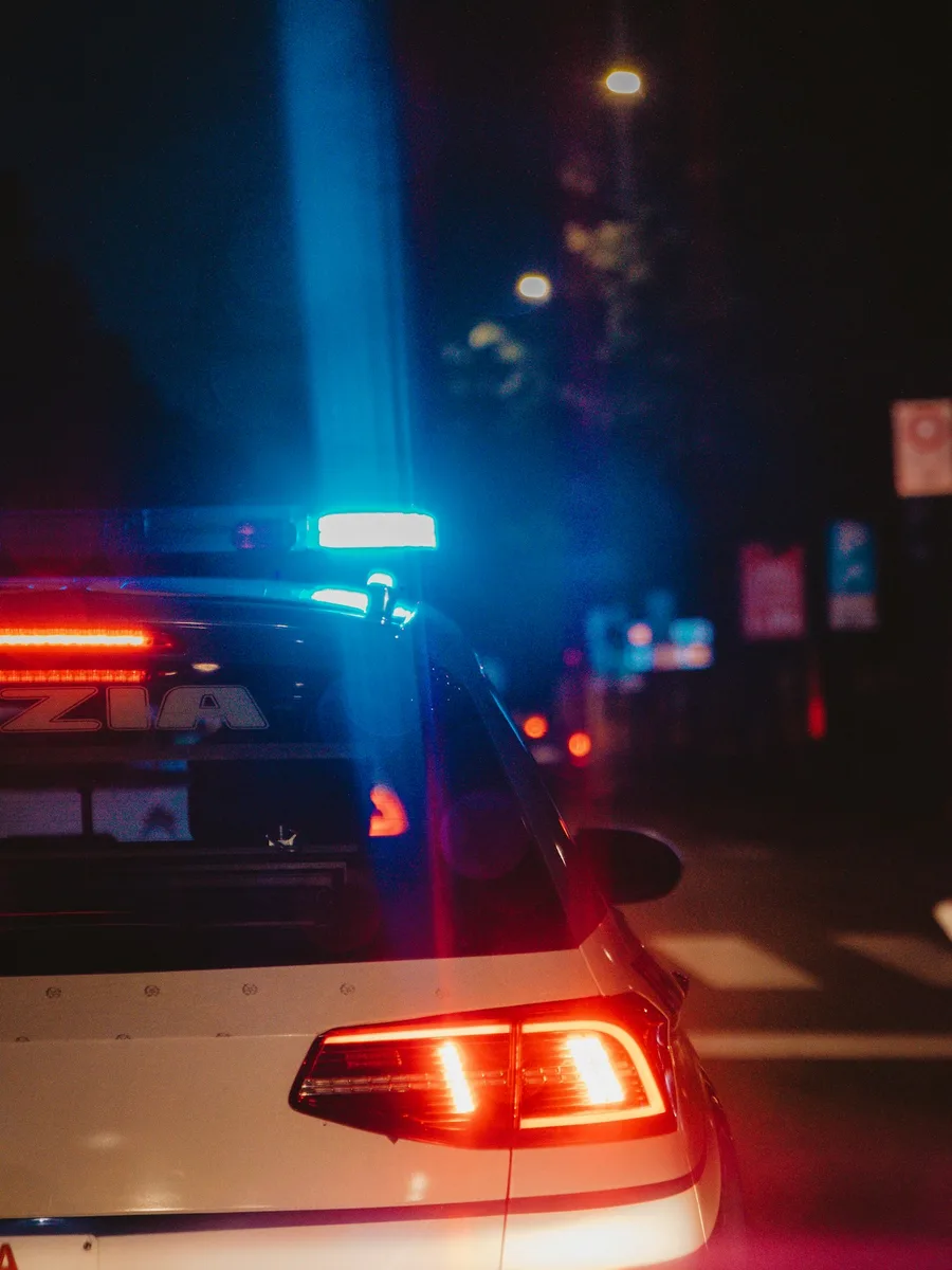 Le gyrophare bleu allumé d'une voiture de police, de nuit, dans une rue éclairée