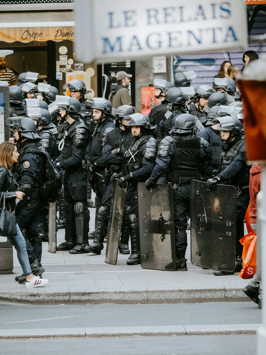 Un cordon de CRS casqués et équipés de boucliers dans une rue de Paris, devant la façade d'un café
