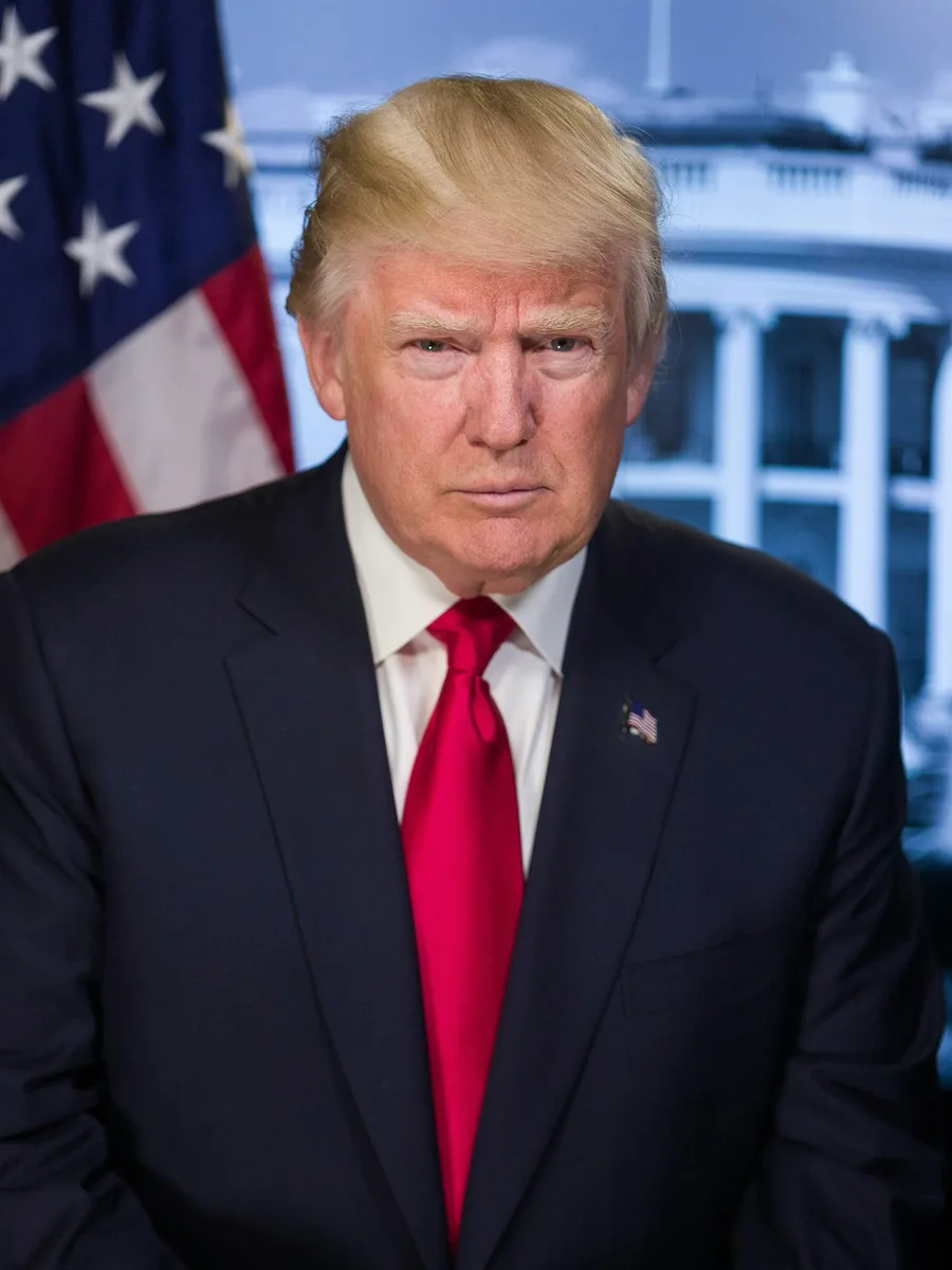 Portrait de Donald Trump en costume sombre et cravate rouge, devant un drapeau américain.