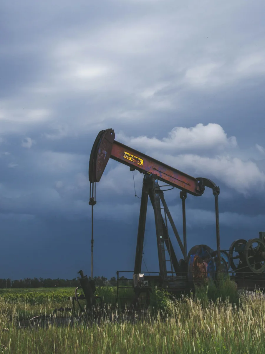 Une pompe à balancier de puits de pétrole dans un champ, sous un ciel d'orage