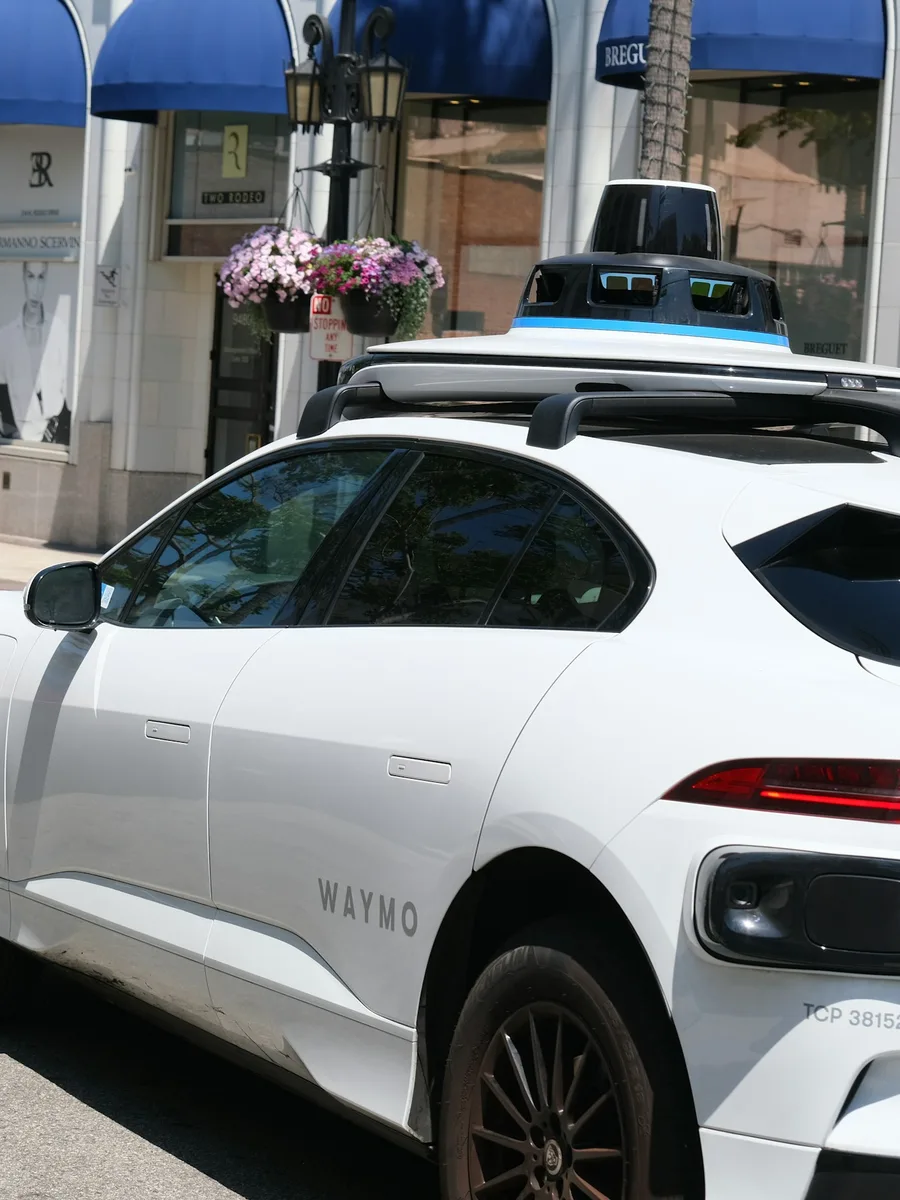 Voiture autonome Waymo blanche, avec ses capteurs sur le toit, stationnée dans une rue