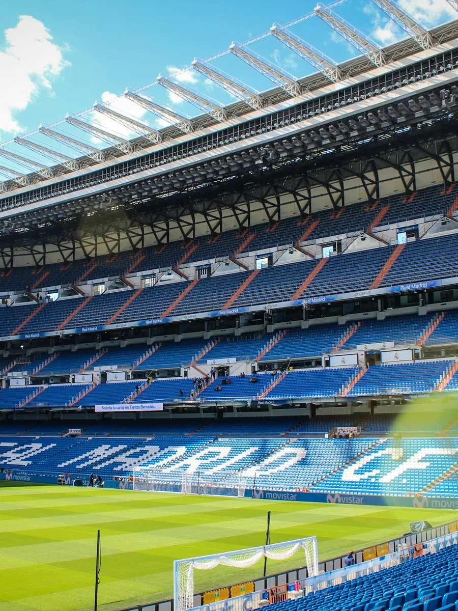 Les tribunes bleues et blanches du stade Santiago-Bernabéu, à Madrid, vides sous un ciel clair.