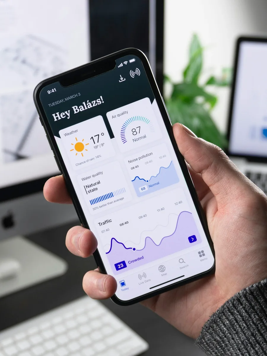 Une main tient un smartphone affichant une application avec des graphiques et des statistiques