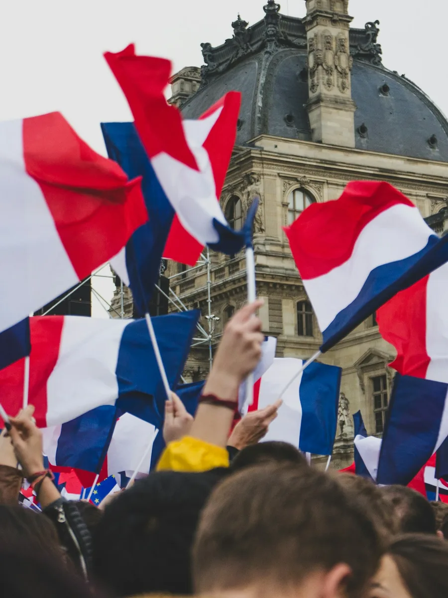 Drapeaux français brandis par une foule devant le Louvre, à Paris