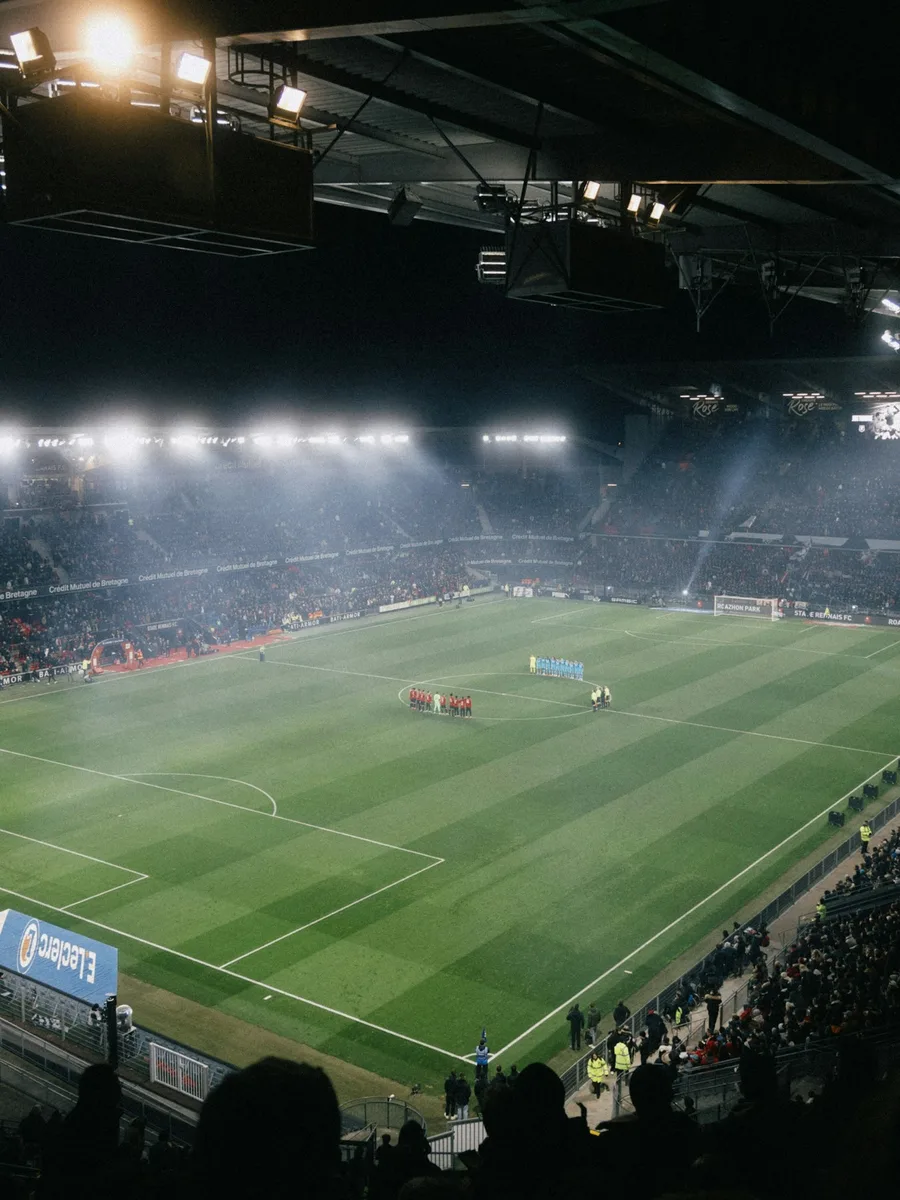 Un stade de football plein, de nuit, sous les projecteurs, lors d'un match Rennes-OM