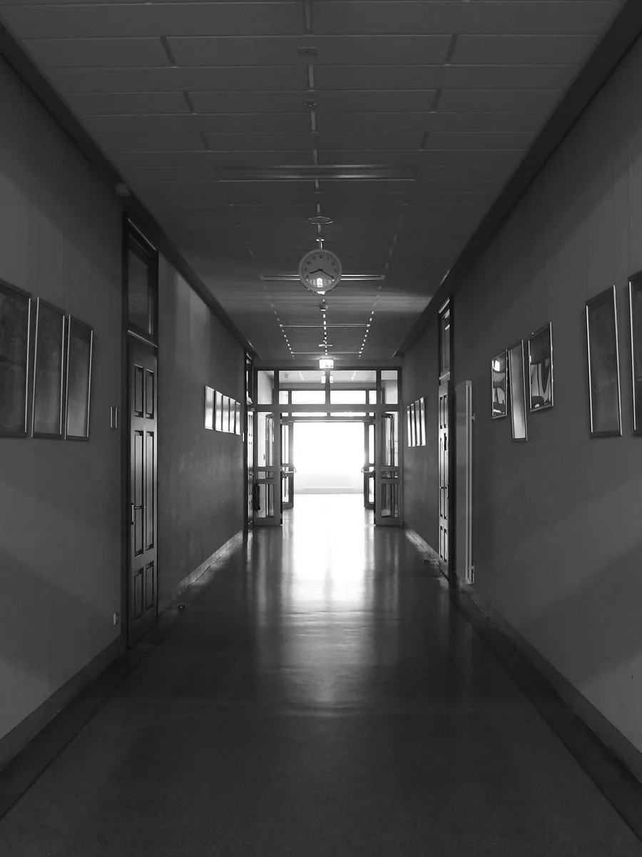 Un long couloir d'école vide, avec des portes et des fenêtres