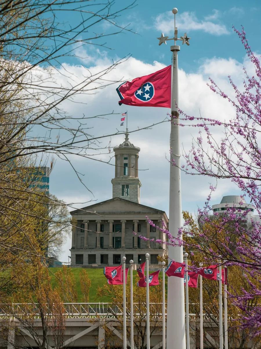 Drapeau du Tennessee flottant au sommet d’un mât, devant le Capitole de l’État à Nashville.