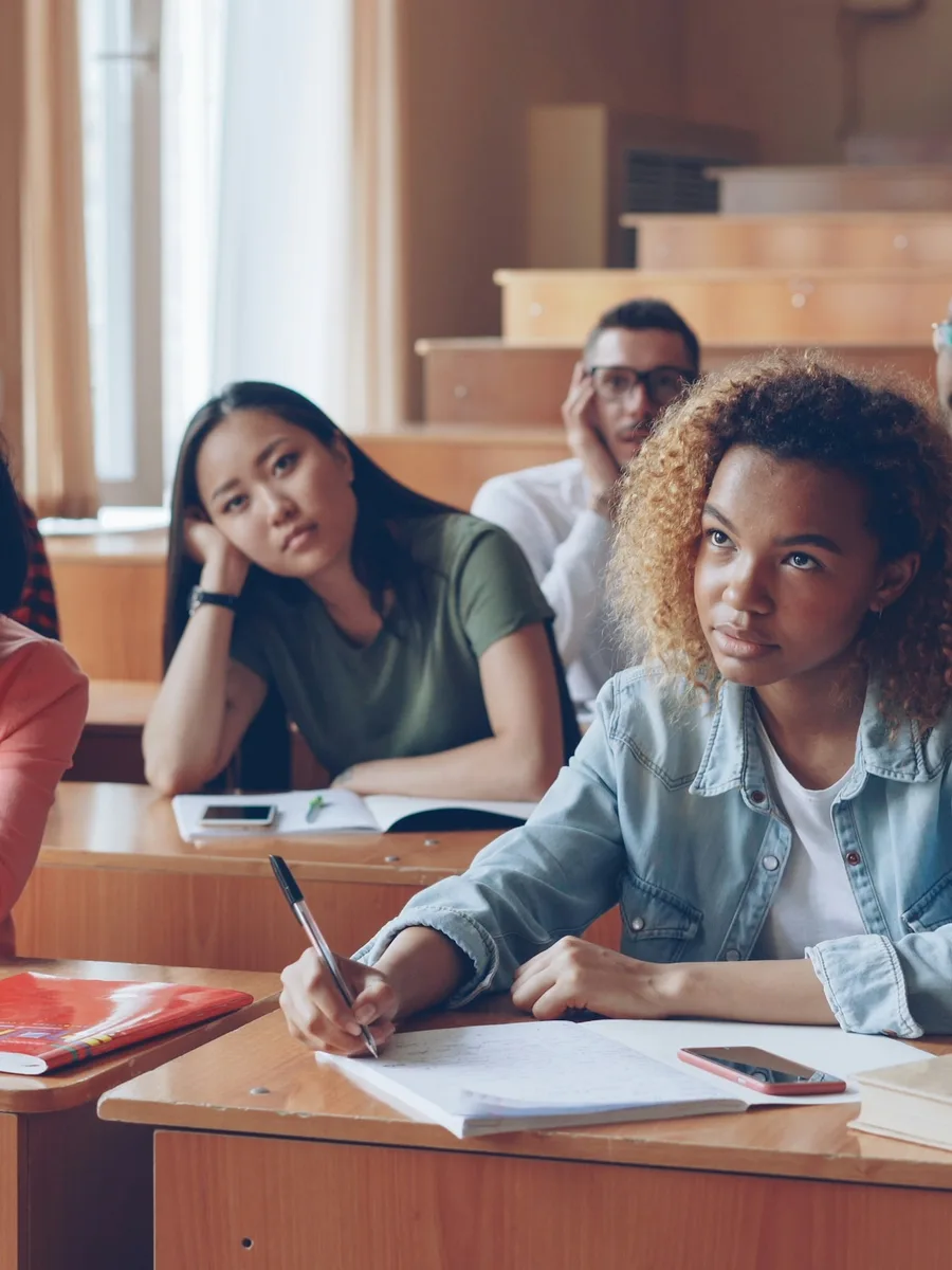 Des étudiantes prennent des notes, assises dans un amphithéâtre pendant un cours.