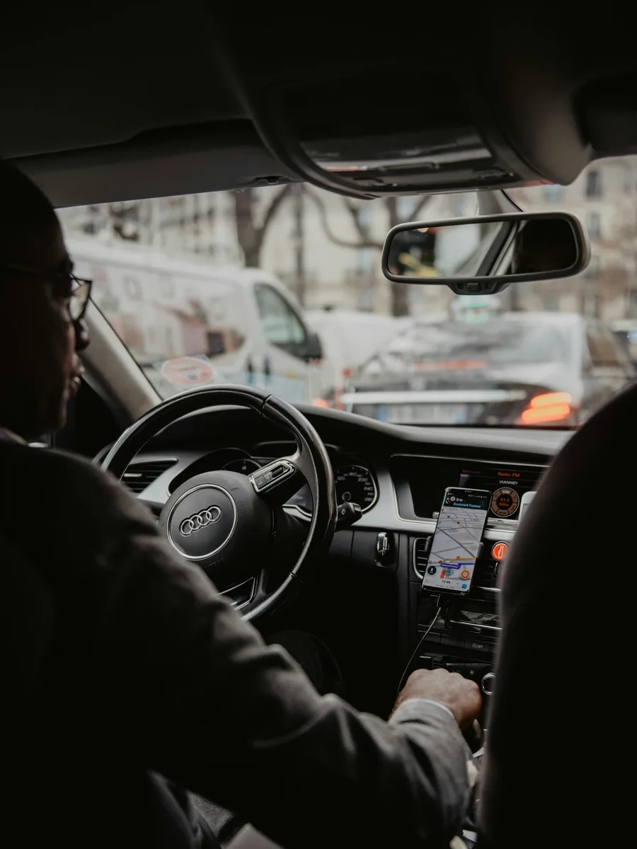 Un chauffeur au volant d'une berline, vu depuis la banquette arrière