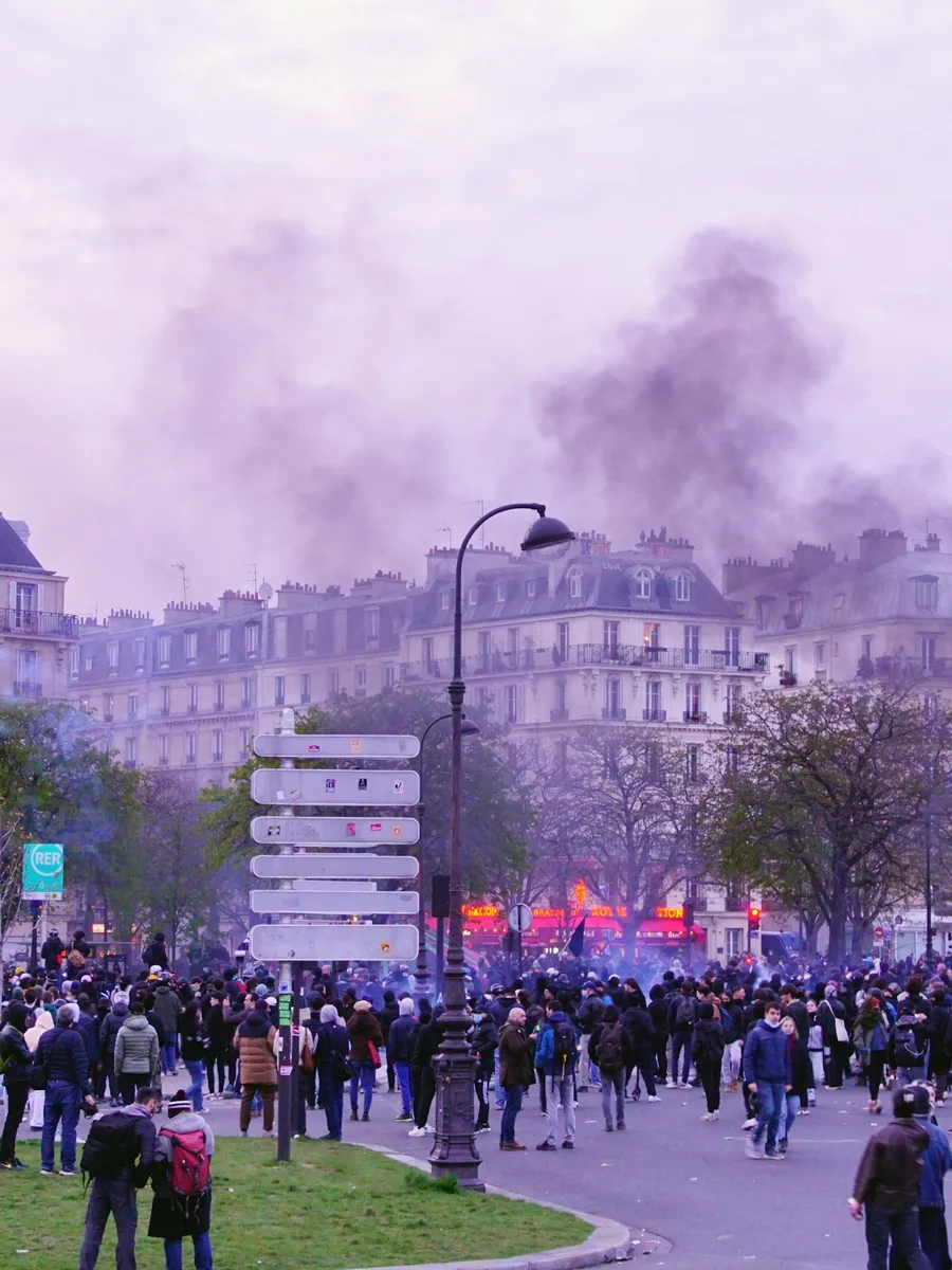 Une foule de manifestants place de la Nation à Paris, de la fumée s'élevant au-dessus des immeubles