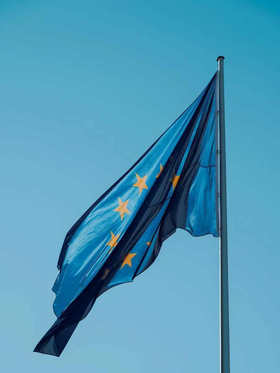 Un drapeau de l'Union européenne flotte au sommet d'un mât sur fond de ciel bleu