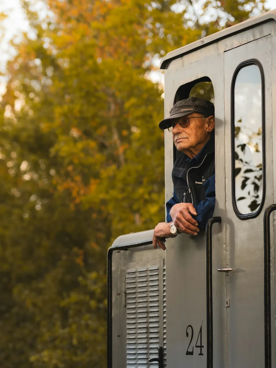 Un homme âgé en casquette se penche à la fenêtre de la cabine d'une locomotive
