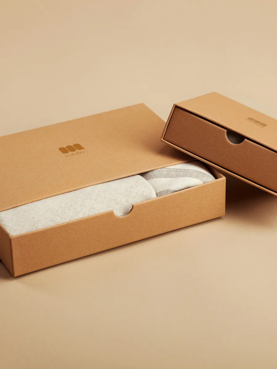 Deux petites boîtes en carton brun, dont une ouverte, posées sur une table
