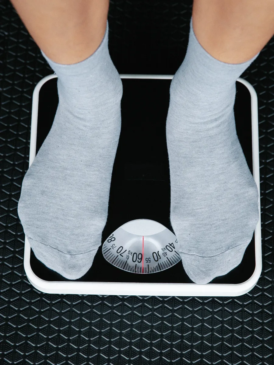 Deux pieds en chaussettes grises posés sur un pèse-personne, vus de dessus