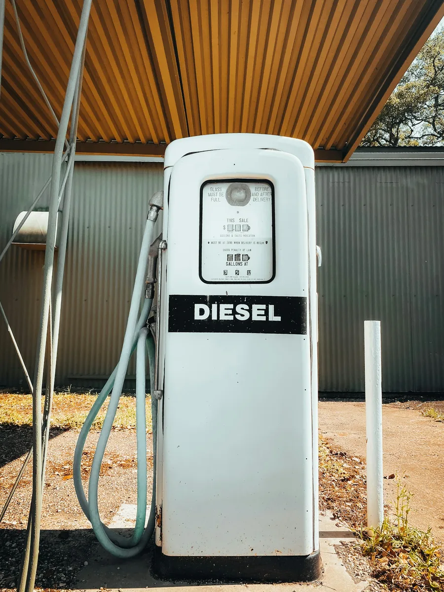 Une ancienne pompe à carburant blanche marquée « Diesel », sous un auvent.