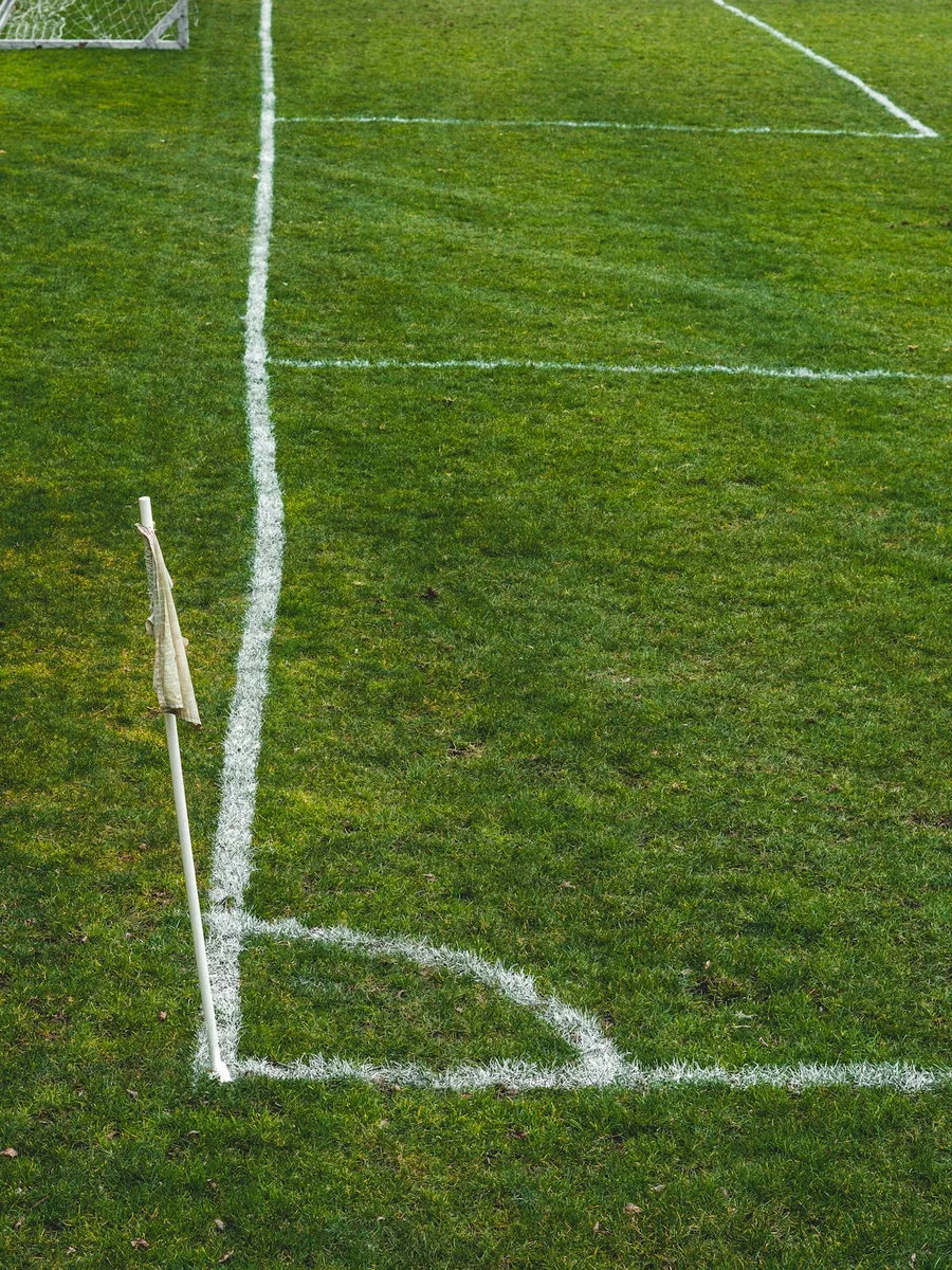 Les lignes blanches tracées sur la pelouse d'un terrain de football, près du drapeau de corner