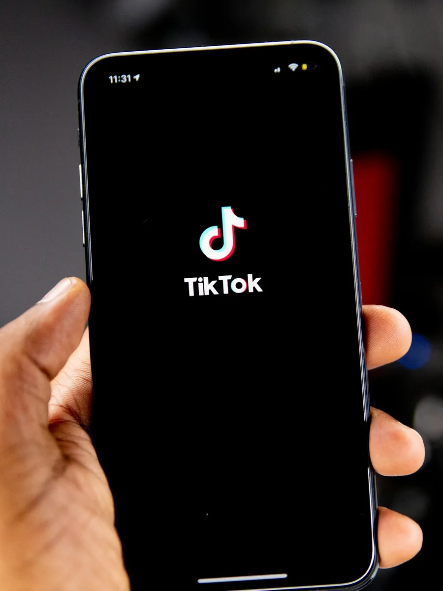 Une main tient un smartphone dont l'écran affiche le logo de TikTok