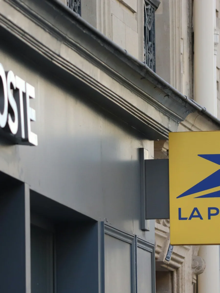 Enseigne et logo jaune de La Poste sur la façade d'un bureau de poste, dans une rue de Paris