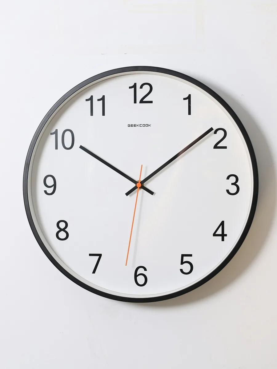 Une horloge murale ronde à cadran blanc et chiffres noirs, accrochée sur un mur blanc