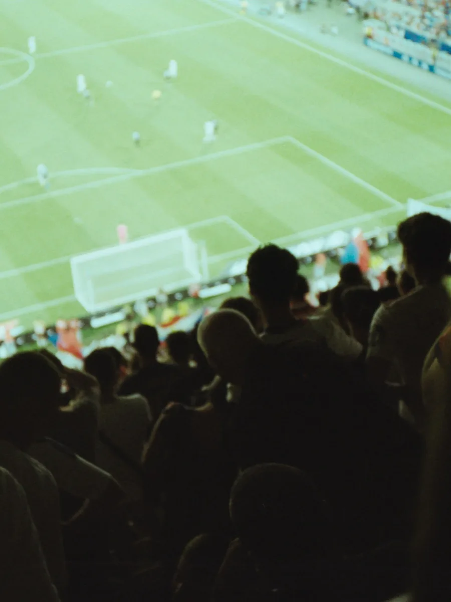 Des spectateurs de dos regardent un match de football depuis les tribunes