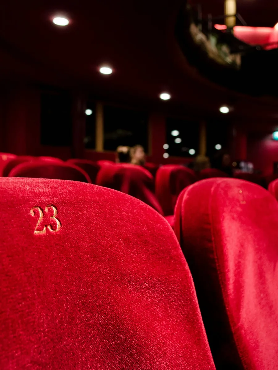 Fauteuils rouges d'une salle de cinéma, avec le numéro 23 visible sur un dossier