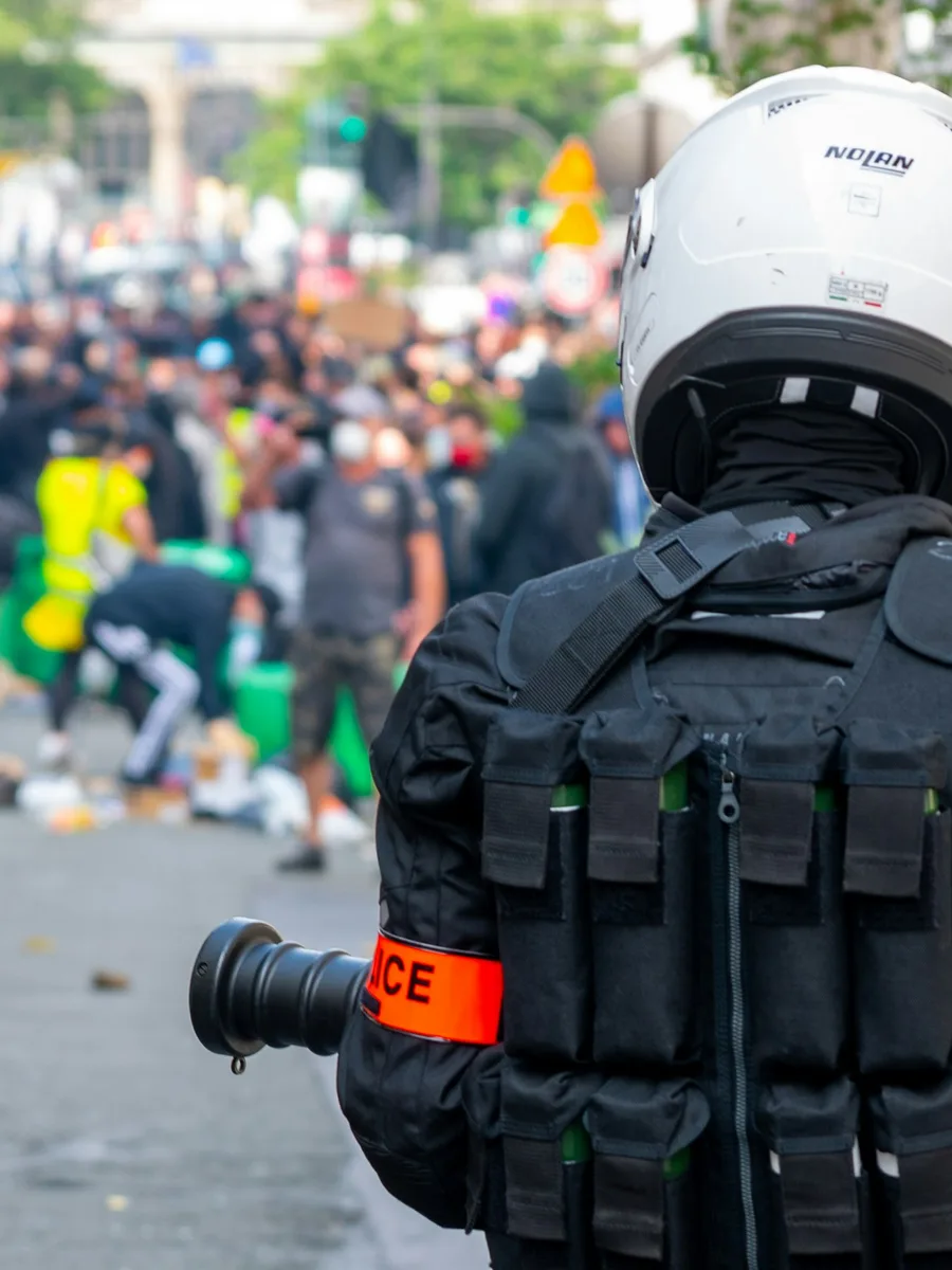 Un policier casqué de dos, face à une foule de manifestants dans une rue de Paris