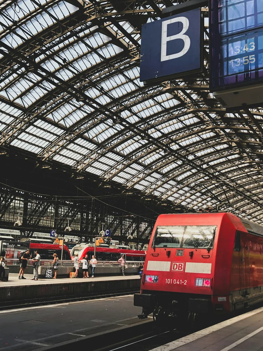 La grande halle de la gare de Cologne, avec un train rouge de la Deutsche Bahn à quai sous la verrière.