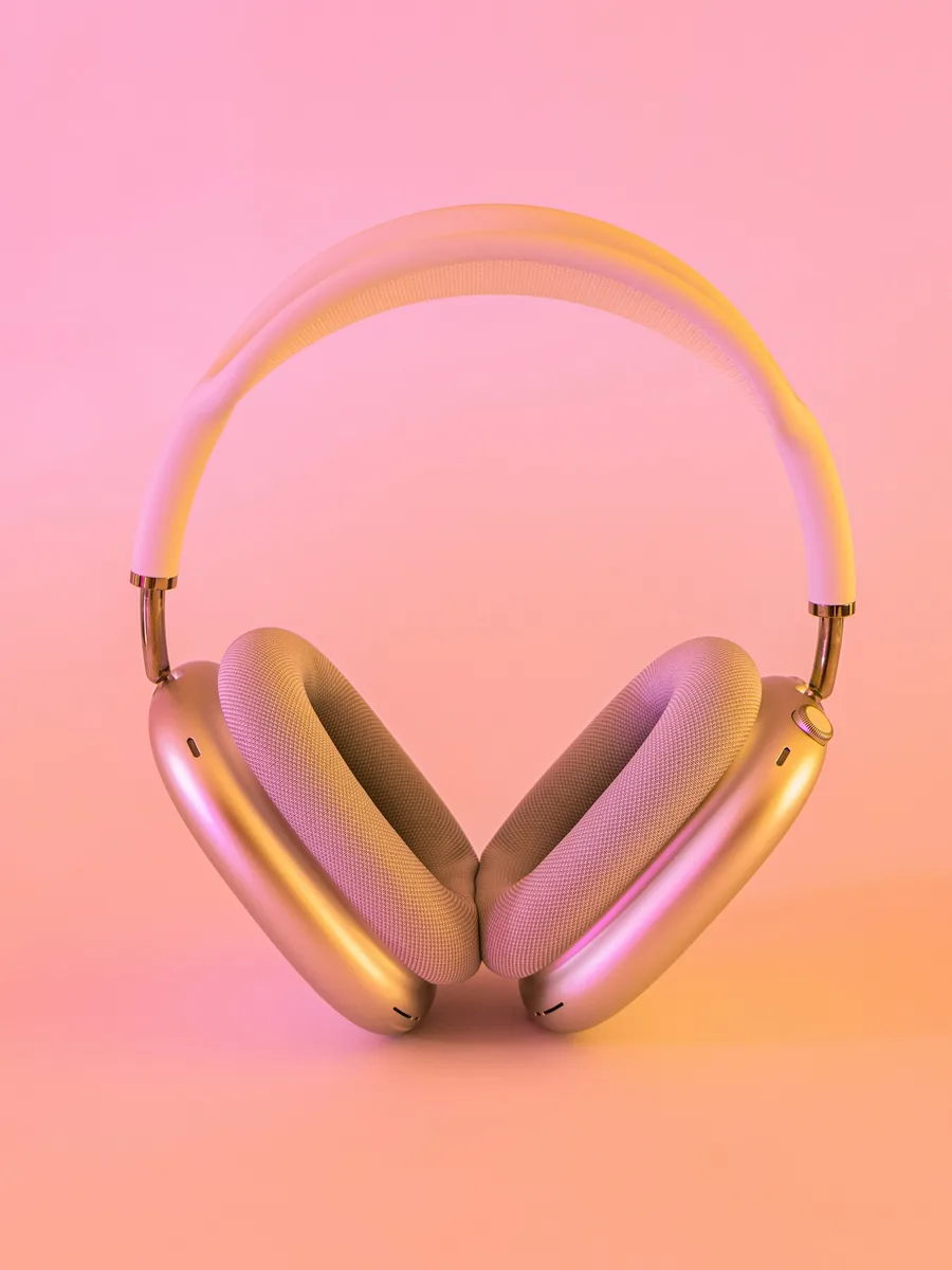 Un casque audio sans fil rose et blanc posé sur une surface, sur fond rose