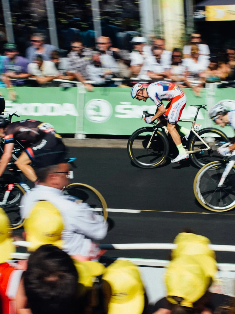 Des spectateurs massés derrière les barrières regardent passer un coureur cycliste lors d'une course