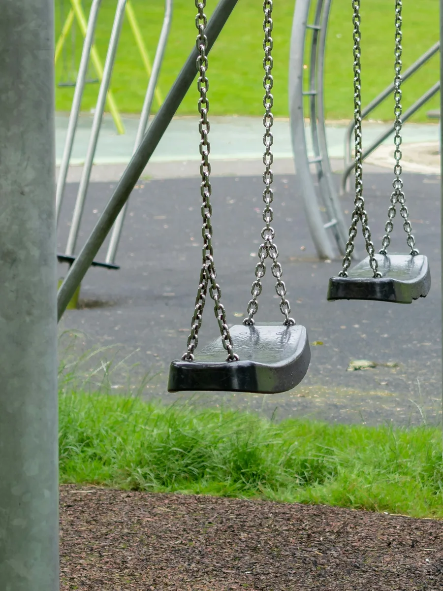 Des balançoires vides suspendues à leurs chaînes dans une aire de jeux