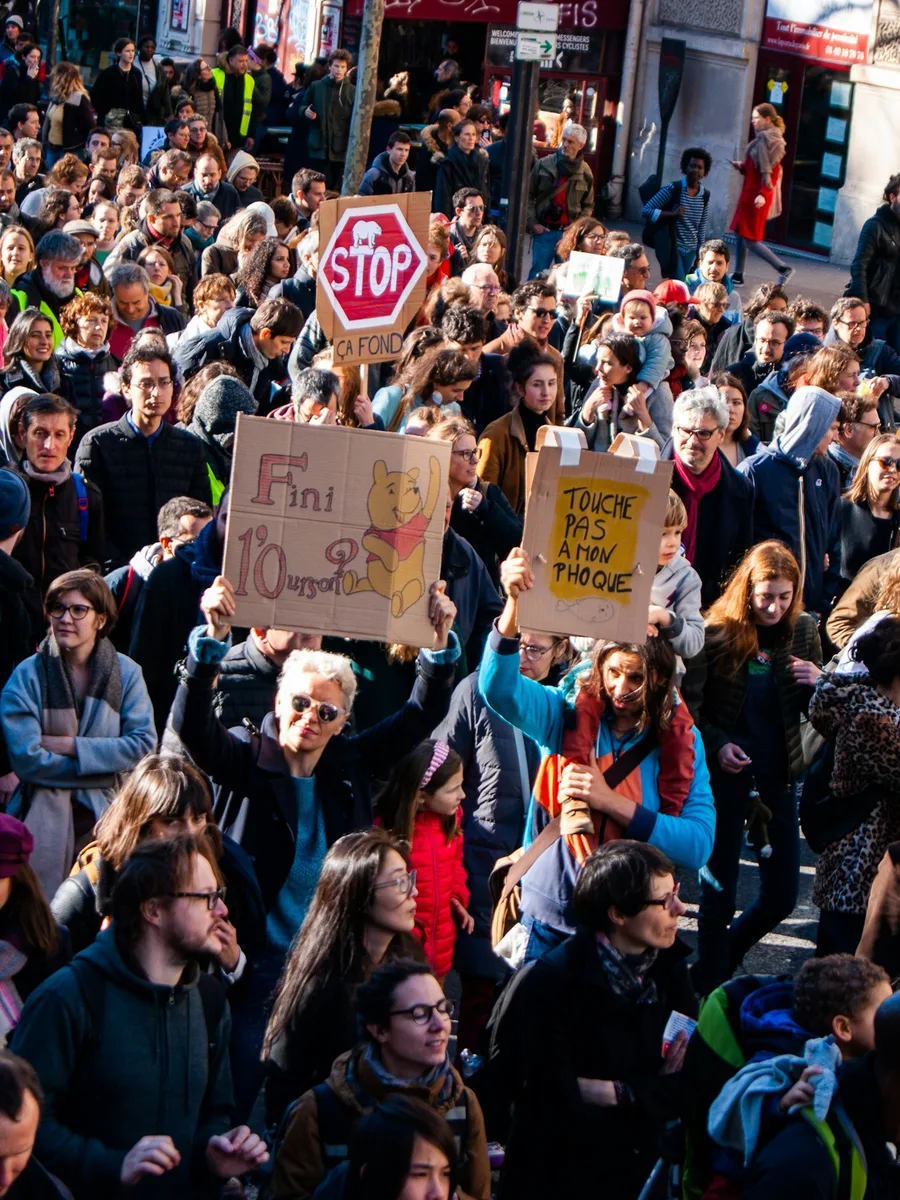 Une foule dense de manifestants tenant des pancartes en carton dans une rue de Paris