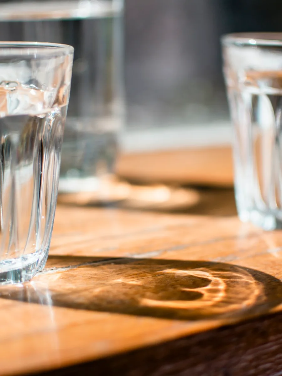 Des verres transparents remplis d'eau posés sur une table en bois