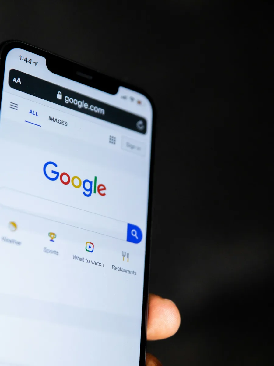 Une main tient un smartphone affichant la page d'accueil du moteur de recherche Google