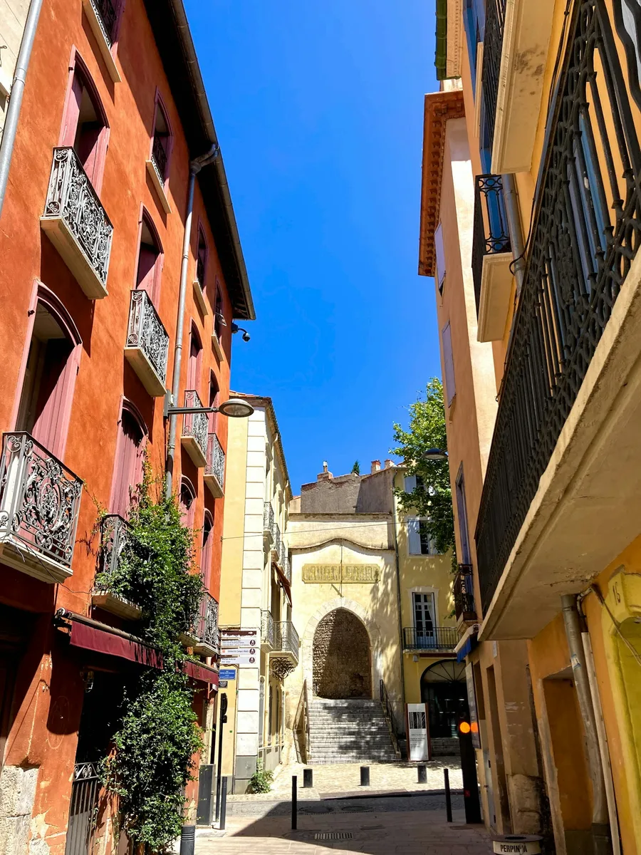 Une rue étroite de centre-ville, entre des façades colorées à balcons