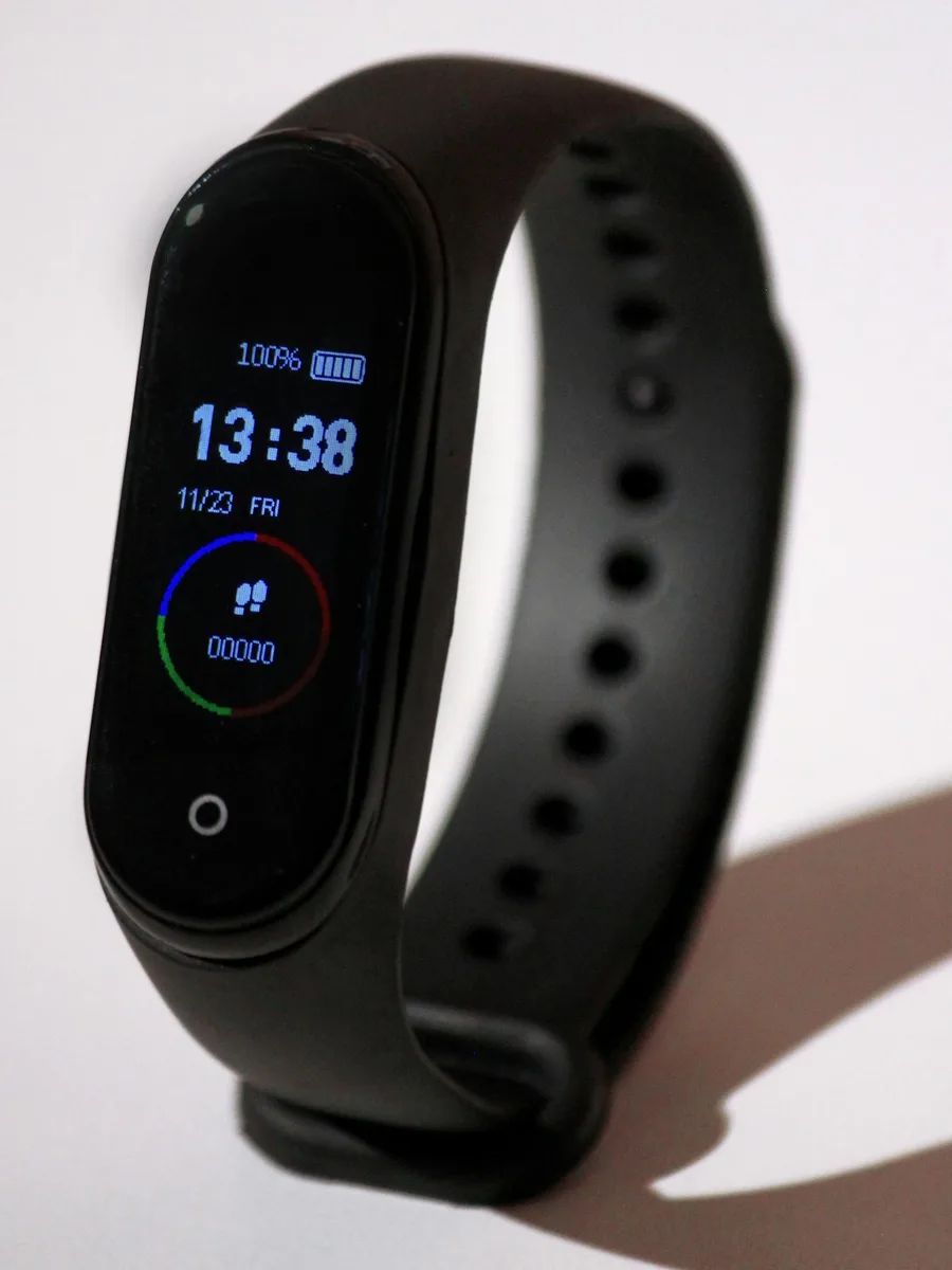 Un bracelet connecté noir dont l'écran affiche l'heure