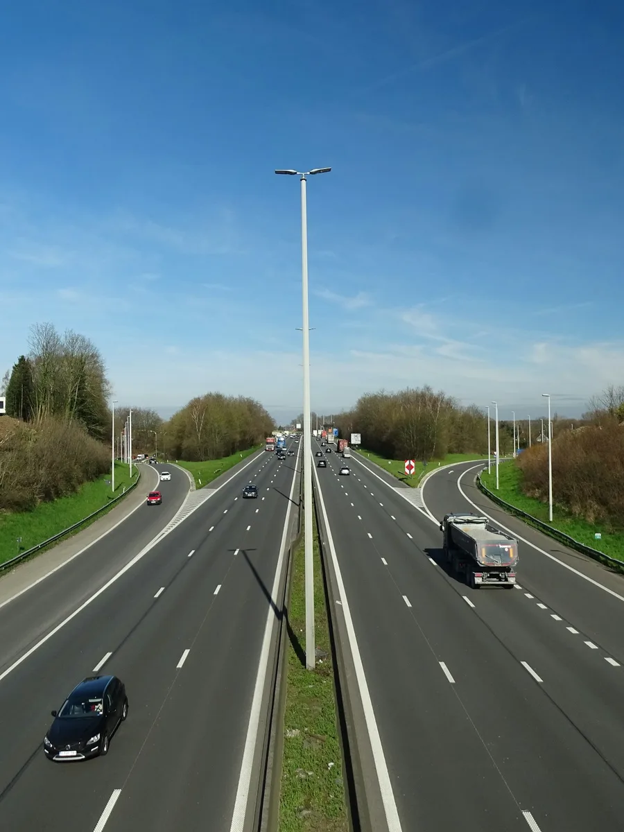 Une autoroute à deux fois deux voies sous un ciel bleu, avec quelques voitures et un camion