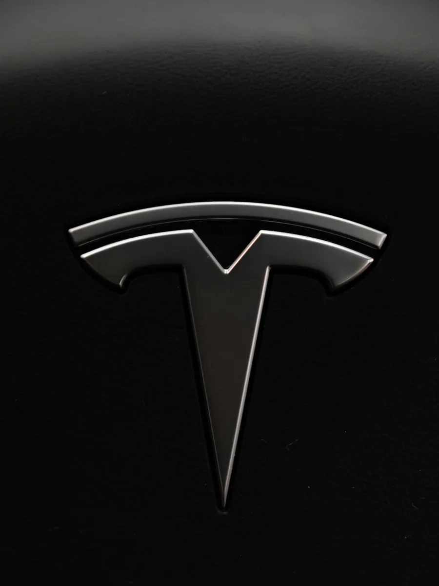 Gros plan sur le logo Tesla chromé sur la carrosserie noire d'une voiture