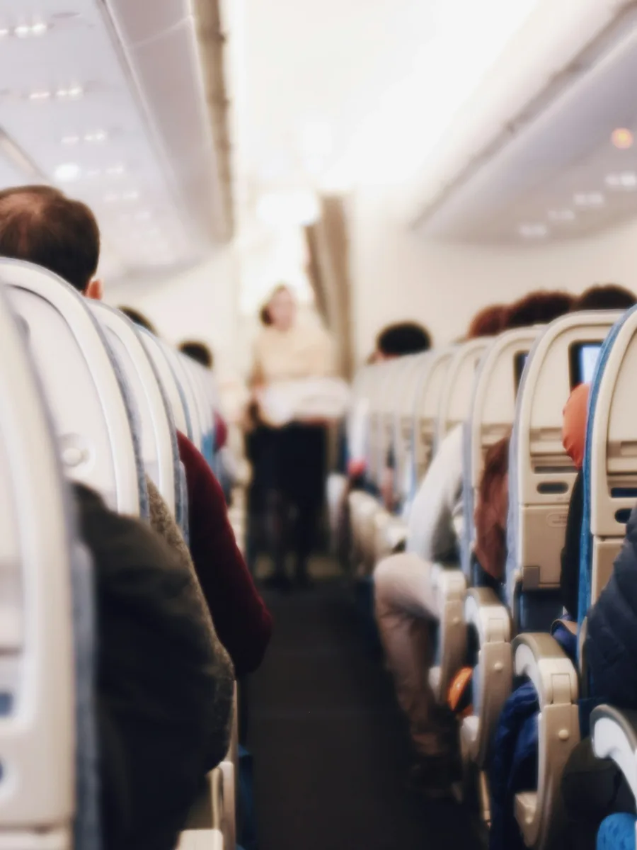 Des passagers assis dans la cabine d'un avion de ligne, vus depuis l'allée